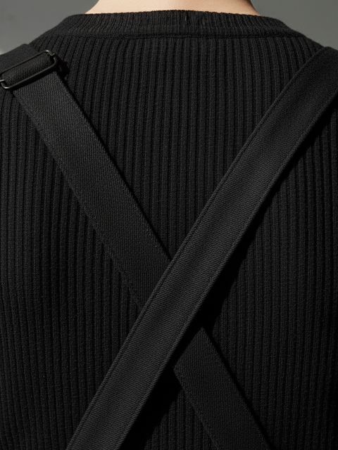 Close-up of the overall’s crossed back straps, worn over a black ribbed knit.